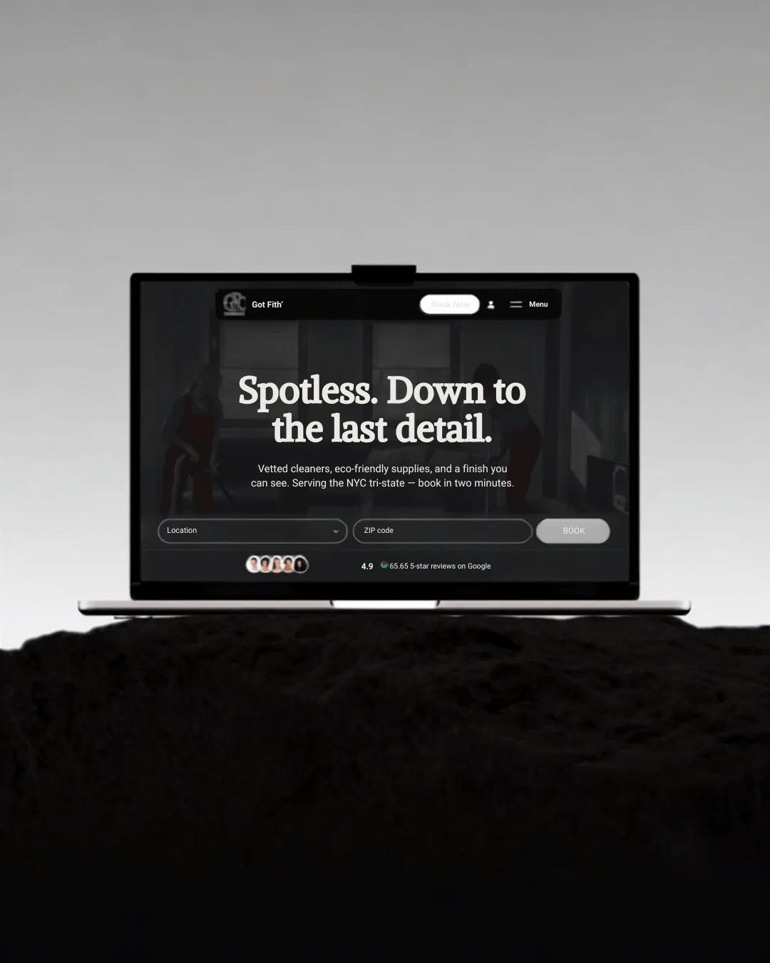 A laptop on black rock under a grey sky, the Got Filth homepage filling its screen — “Spotless. Down to the last detail.”