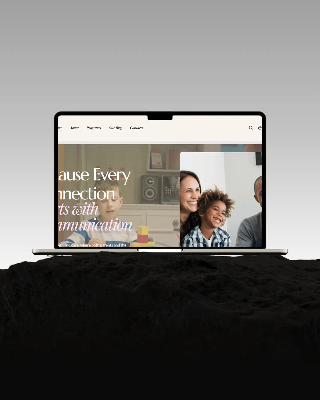A laptop on black rock under a grey sky, the Growth in Connections homepage filling its screen — a child at play and a family together